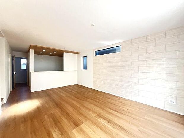 明るさが広がるリビングは木目調の床が温かみを演出しています。レンガ調の壁面がアクセントとなりすっきりとした印象です。広々とした空間が開放感を与えます。配線コンセントも便利な位置に設置されています。