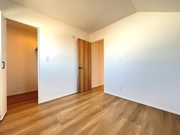 明るいフローリングが印象的な洋室です。シンプルな壁紙と木目調の扉が調和しすっきりとした空間を演出しています。収納スペースも備わった使い勝手の良い一室です。