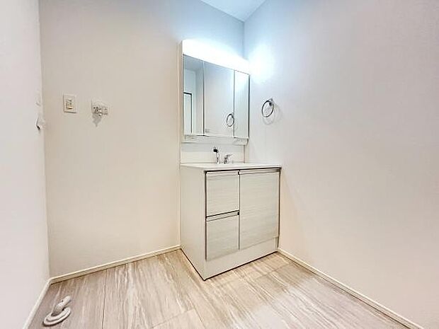 シンプルで清潔感のある洗面台が設置されています。収納スペースも豊富で使い勝手の良さが感じられます。広々とした空間が確保されており日々の身支度にも便利です。照明付きのミラーが明るさをサポートします。