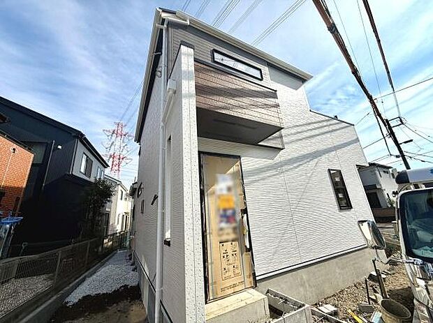 外観のシンプルなデザインが印象的です。玄関は建物の角に配置され独立性があります。明るい日差しを受ける立地です。建物全体に清潔感が感じられます。新築ならではの状態です。