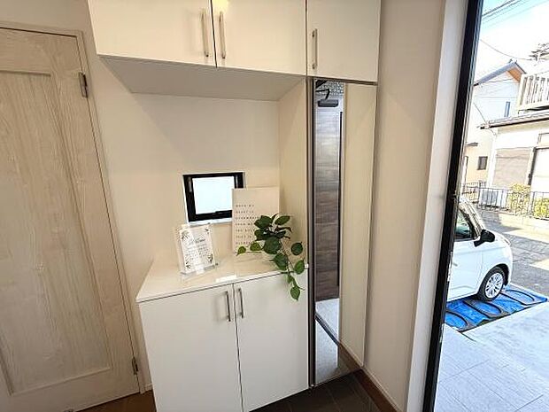 玄関には使いやすい収納スペースが設けられております。大きなミラーもあり身だしなみのチェックに便利です。明るい窓から光が入り玄関全体が開放的に感じられます。