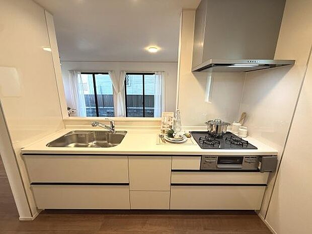 収納スペースが豊富で使いやすいキッチンです。落ち着いた色合いのデザインが空間に調和しています。3口コンロと広めのシンクが備わっています。作業がしやすいレイアウトです。