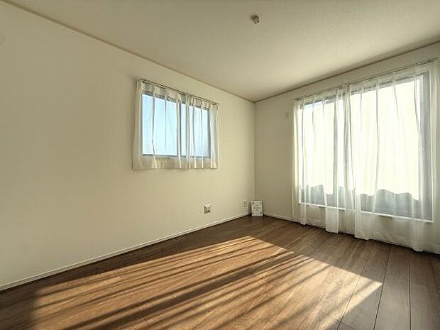 二面採光で明るさが広がる洋室です。シンプルな内装でインテリアが映えます。窓からの日差しが心地よく入ります。床の色合いが空間を引き締めます。カーテン付きの仕様もポイントです。