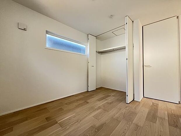 明るい色合いのフローリングが特徴ですっきりとした印象の洋室です。クローゼットが備え付けられているので収納も充実しています。横長の窓が採光を確保し室内を明るく保ちます。