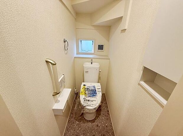 コンパクトながらも明るい印象のトイレ空間です。手すり付きで安心してご利用いただけます。小窓があり換気や自然光の取り入れが可能です。収納スペースも設けられ日用品の整理に便利です。