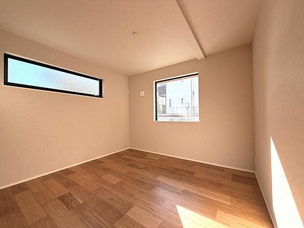 二面採光で日差しが差し込む洋室です。シンプルな内装が特徴的で空間を広く感じられます。フローリングの質感が魅力的です。窓の配置が工夫されており通風も良好です。
