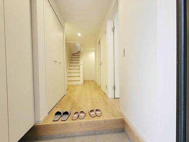 玄関にはゆとりのある空間が広がっています。明るい照明が奥行きを感じさせ清潔感のある内装が印象的です。シンプルなデザインが特徴となっています。収納スペースも整っている玄関です。