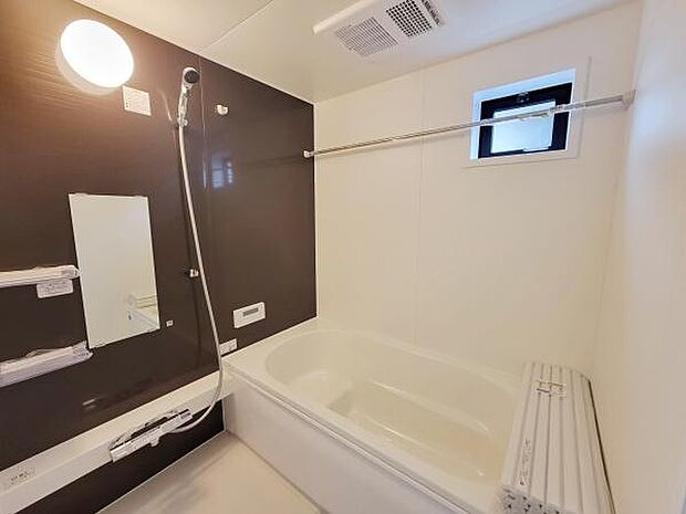 清潔感のあるバスルームです。窓付きのため換気がしやすい設計となっています。壁面の配色がアクセントとなり空間を引き締めています。浴槽にはフタも設置されています。