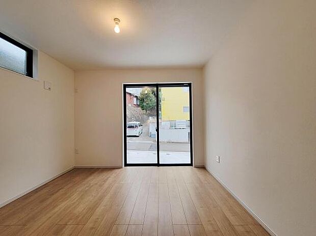 大きな窓から自然光がしっかり入る洋室です。シンプルな内装でインテリアの自由度が高い空間です。床は木目調で落ち着いた雰囲気を演出します。清潔感のある室内に仕上がっています。