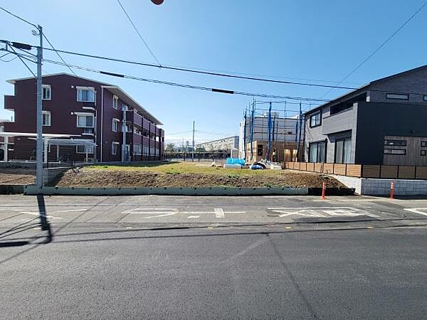前面道路が広く確保されている現地写真です。周辺には新しい建物やマンションが並んでおり整った街並みが特徴です。日当たりも良く開放感のある立地が印象的です。現地の雰囲気をしっかり確認できます。