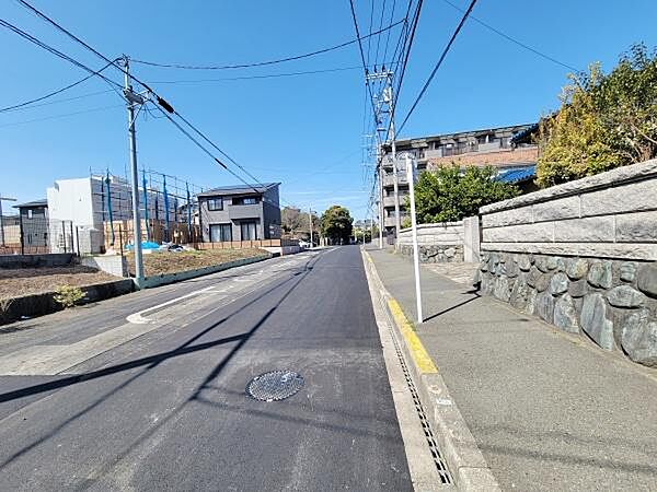 前面道路は広々としており車両の通行がしやすい環境です。舗装された歩道も整備されており快適に歩行いただけます。周囲には住宅や施設が整然と並んでいます。道路沿いの視界も良好です。