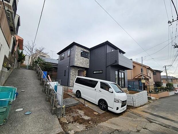 現代的なデザインが特徴的な外観です。石調のアクセントが建物に個性を与えています。道路に面した駐車スペースも便利に使えます。周囲には戸建てが多く穏やかな住宅地の印象です。