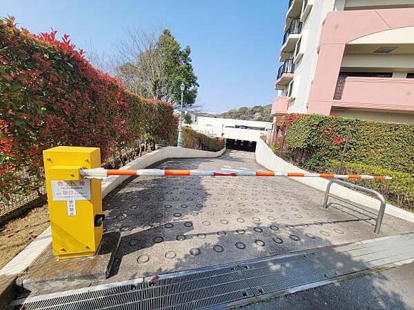駐車場入口にはバーが設置され住民の利便性と安全性が配慮されています。舗装も丁寧で車両の進入がスムーズです。周囲の植栽がしっかり手入れされており明るい印象です。建物も清潔感があります。