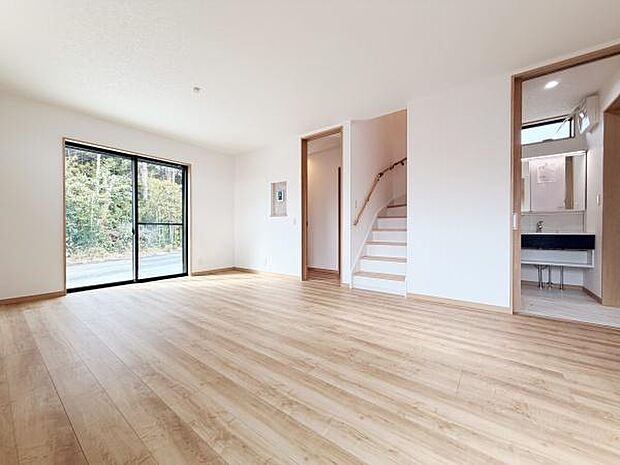 大きな窓から光が広がる明るいリビングです。ナチュラルなフローリングが空間を引き立てています。開放感のある設計が魅力的です。階段や洗面スペースへのアクセスもスムーズです。