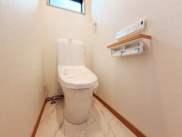 清潔感のあるトイレ空間です。ゆったりとしたスペースで使いやすい設計になっています。窓があり換気もしやすい環境です。収納棚付きで便利です。操作パネルも見やすい位置にあります。