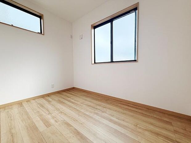 シンプルな内装の洋室です。二面に設けられた窓が明るさを確保しています。木目調のフローリングが温かみを感じさせます。壁や天井はホワイトトーンでまとめられています。すっきりとした印象の空間です。