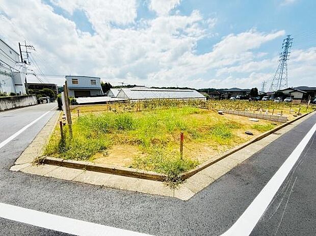 明るい日差しが差し込む前面道路に接した現地写真です。周辺には開放感があり区画もすっきりしています。両面道路の角地となっており見通しの良い立地が特徴です。造成済みの敷地で即時利用が可能です。