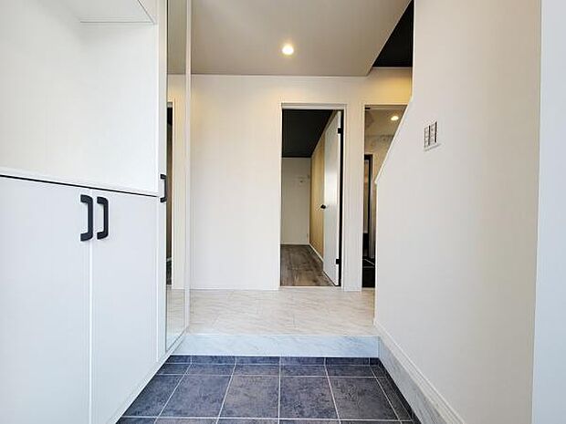 すっきりとした玄関スペースが印象的です。収納スペースも設けられており使いやすさが感じられます。明るい色合いの壁と床が空間を広く見せます。鏡面の扉でより開放感も感じられる設計です。