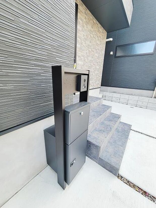 シンプルで洗練されたデザインの玄関周りが印象的です。段差が緩やかで安全性にも配慮されています。ポストが使いやすい位置に設置されています。外壁の質感と調和した色合いも魅力のひとつです。