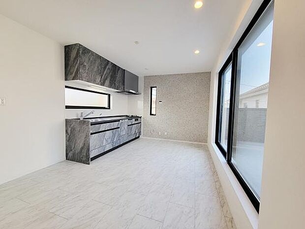 窓が大きく明るい光がたっぷりと差し込むキッチンです。シンプルな内装が空間を広く感じさせます。スタイリッシュなデザインのキッチンが印象的です。収納スペースも充実しています。