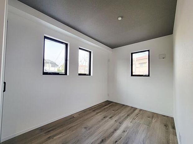 洋室には3つの窓があり室内に光を取り入れやすくなっています。白を基調とした壁と木目調の床が印象的です。天井の色がアクセントになり落ち着いた雰囲気を演出しています。ゆとりある空間設計がされています。