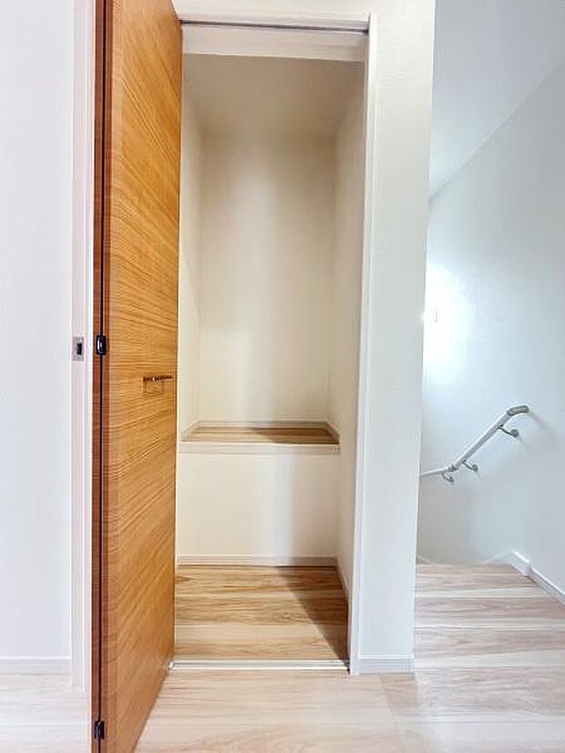 扉付きの収納スペースが用意されています。階段付近に配置されていて利便性が感じられます。木目調のデザインが室内に調和しています。空間がすっきりと見えます。収納内部も清潔感があります。