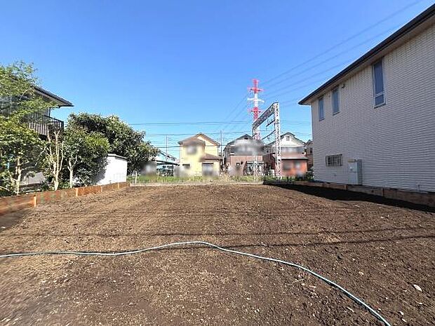 日当たりの良い広々とした現地土地写真です。周囲に住宅が並び落ち着いた雰囲気が感じられます。整地済みで次のステップに進みやすい環境です。現況が分かるため検討しやすい一枚となっています。