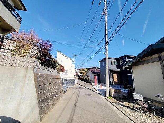 前面道路がすっきりと整備されており車の出入りがしやすい印象です。静かな住宅街の一角で周囲には新しい建物も見られます。現地は開放感があり圧迫感を感じにくい環境です。