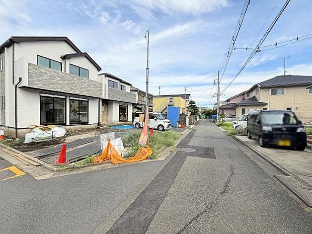 現地の前面道路は車通りが落ち着いており見通しの良い直線道路が続いています。周辺は戸建てが並ぶエリアで静かな街並みが広がっています。角地に位置しているため敷地が広く感じられます。