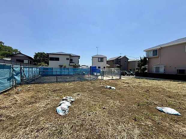 現地土地写真から整地された広々とした敷地がよくわかります。周囲には住宅が立ち並び落ち着いた雰囲気です。陽当たりも良好です。