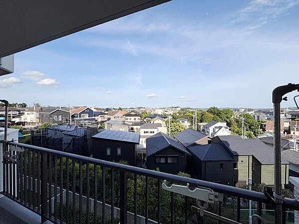 バルコニーから広がる眺望が魅力の一枚です。戸建てや緑が点在し周囲の住宅街が見渡せる開放的な景色です。建物の高さにより視界が遮られず遠くまで見渡すことができます。晴れた日の青空が印象的です。