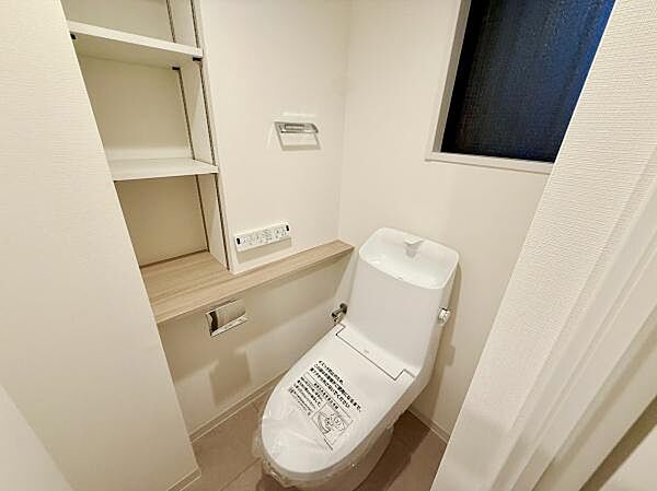 棚が備え付けられており収納がしやすいトイレです。窓があるため換気も可能です。シンプルなデザインで清潔感を感じられます。カウンター付きでちょっとした小物も置ける仕様です。