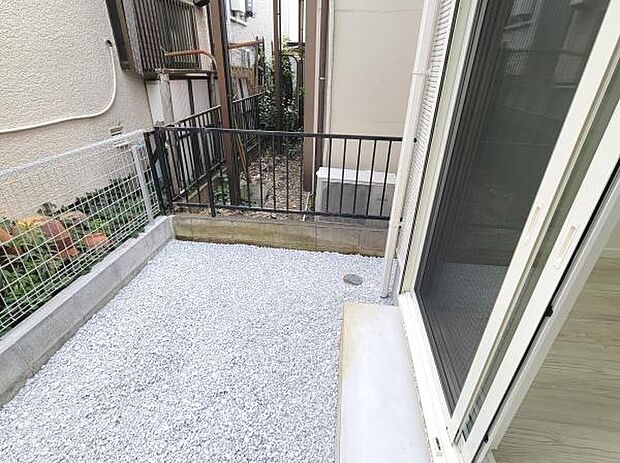 室外に面したスペースが確保されており気軽にお手入れができます。柵が設置されているため安心感があります。白い砂利が敷かれているのですっきりとした印象です。掃き出し窓から直接アクセス可能です。