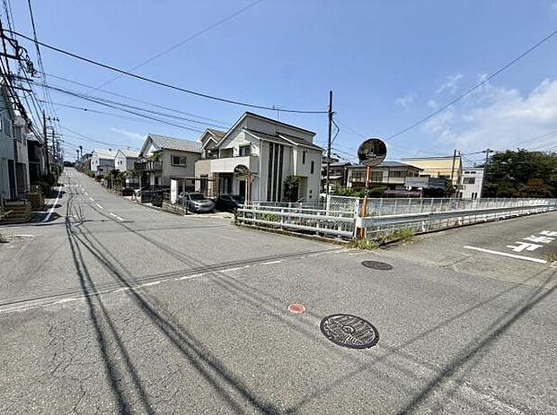 現地周辺は見通しの良い道路が広がり周囲の建物も落ち着いた雰囲気です。車の通行にも配慮された道幅が確保されています。すぐそばには橋があり街並みにアクセントを加えています。