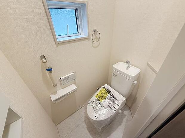 窓が設置されており換気がしやすいトイレです。シンプルな内装で落ち着いた雰囲気となっています。ペーパーホルダーやタオルリングも備わっていて使いやすい空間です。壁付けのスイッチパネルがあり操作も簡単です。