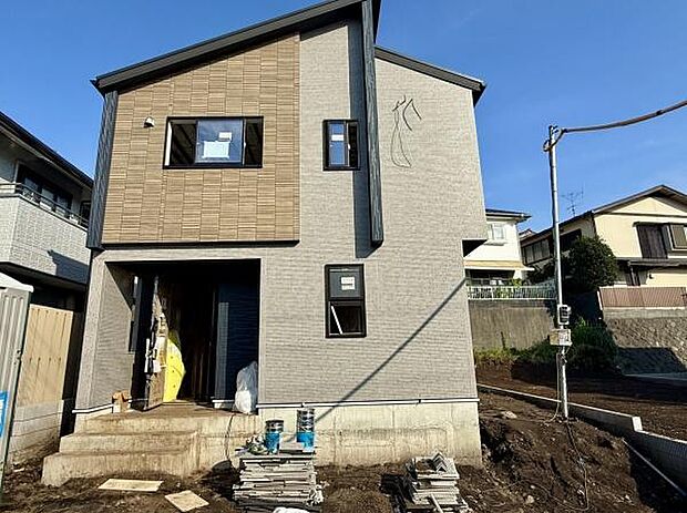 落ち着いた色合いの外観で現代的な印象を与える住まいです。窓の配置が工夫されておりバランスの良いデザインが魅力的です。玄関部分もゆとりがあり快適に出入りできます。敷地も広くさまざまな活用が可能です。