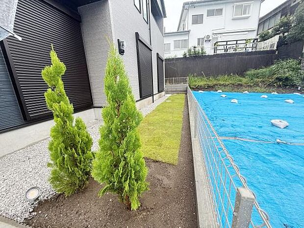 緑豊かな植栽が印象的な庭です。日当たりの良いスペースでシンプルなデザインが特徴です。隣地との間にフェンスが設けられており安心感があります。手入れしやすい芝生の配置がポイントです。
