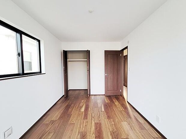 クローゼット収納が備わっている室内です。シンプルなデザインが空間をすっきりと見せてくれます。木目調のフローリングが落ち着いた雰囲気を演出しています。窓からの光が明るさをプラスしています。