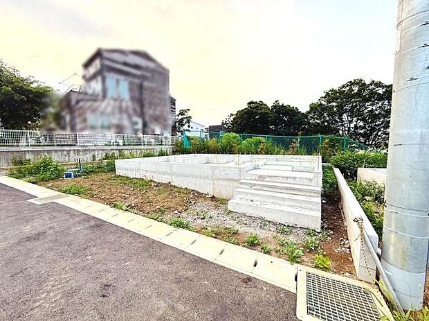 舗装された前面道路に面しており敷地までのアクセスがスムーズです。周辺には緑も多く開放感があります。道路幅も十分に確保されていて車の出入りも便利です。日当たりも良好な現地写真です。