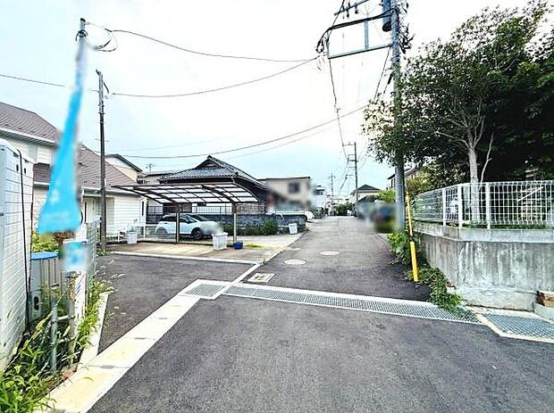 道路は広々としており車の出し入れもスムーズに行えます。周辺は住宅街で落ち着いた雰囲気が感じられます。舗装された道路が敷地へのアクセスをサポートします。電柱やフェンスもしっかりと整備されています。
