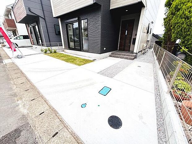 建物前面に広々とした駐車場スペースが確保されています。コンクリート舗装で整備されておりお手入れも簡単です。隣接道路からのアクセスもスムーズになっています。駐車場周辺には緑地も配置されています。