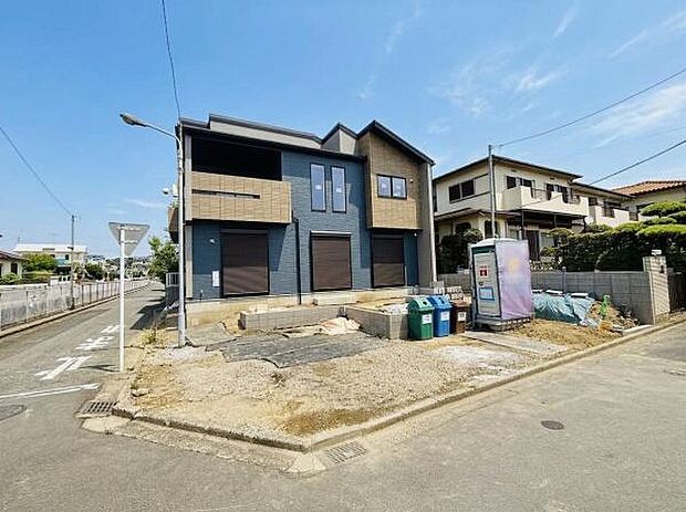 建物が角地に位置し開放感が広がる現地写真です。前面道路が広く車の出入りがしやすい環境です。周辺は住宅が整然と並び落ち着いた雰囲気が感じられます。日当たりも良好な立地となっています。
