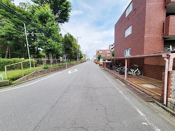 落ち着いた雰囲気のある道路に面した立地です。目の前には緑が多く開放感が感じられます。自転車置き場もゆとりを持って設けられています。周囲に高い建物が少なく空が広く見渡せます。