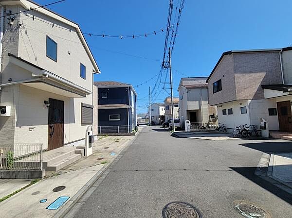 陽当たりの良い現地建物と前面道路の写真です。建物周りがゆったりとしたスペースで確保されています。駐車スペースも広く車の出し入れがしやすそうです。閑静な住宅街の一角で周囲も整った街並みが感じられます。