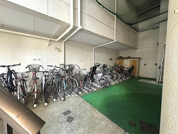 駐車場スペースがしっかりと確保されており自転車が多数収納されています。屋内型のため雨風の影響を受けにくい環境です。床がコンクリートと人工芝で分かれておりきれいに整頓されています。