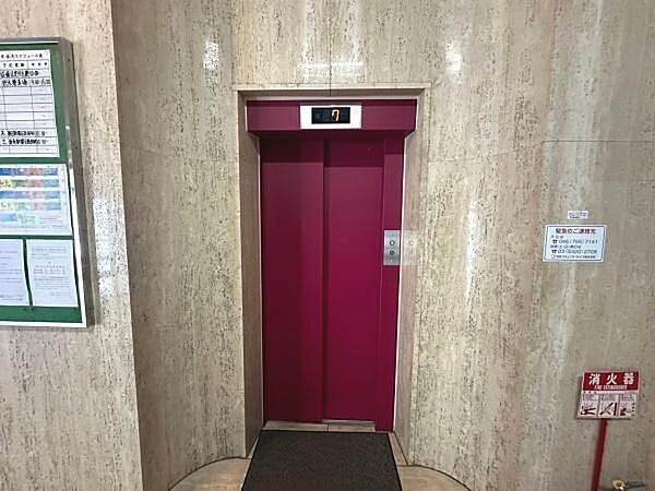 赤色のエレベーターが目を引くデザインです。シンプルながらも周囲になじむ内装が特徴的です。案内掲示板や消火器も設置されています。利便性を感じさせる空間です。管理体制に配慮された印象があります。