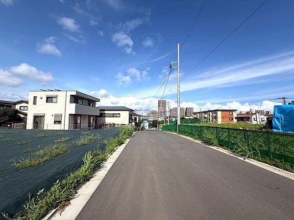 青空のもと整備された道路が広がる落ち着いた住宅街が印象的です。車の出入りもしやすく周辺には新しい住宅や整備された土地が見受けられます。道路幅もゆとりがあり視界も開けています。
