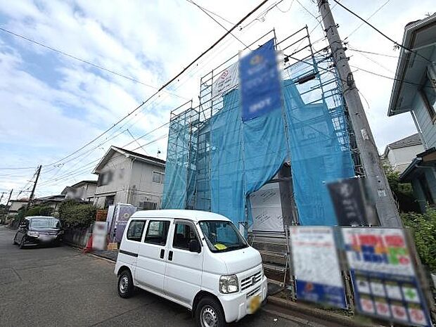 建築中の物件が青いシートで丁寧に囲われており工事の進行状況が分かりやすい外観です。前面道路は広めで車の出入りもスムーズです。周辺は落ち着いた住宅街で静かな環境が魅力です。