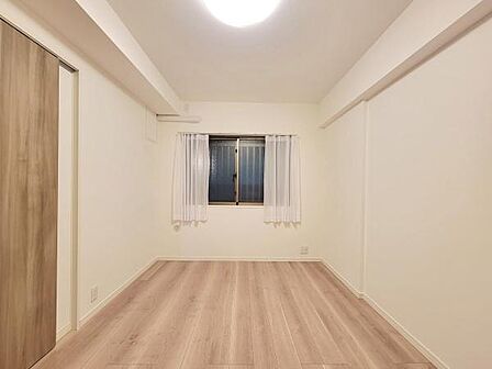 明るい照明とナチュラルな床材が印象的な寝室です。窓からの採光も確保されており白を基調とした壁面が広さを感じさせます。収納スペースも備わっており整理整頓がしやすい設計となっています。