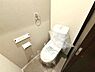 トイレ：シンプルなデザインのトイレです。手洗い器一体型で使いやすい仕様となっています。壁面にはペーパーホルダーやタオルリングが設置されています。床や壁も落ち着いた色合いでまとめられています。